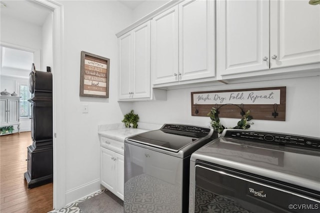 laundry area with cabinets, hardwood / wood-style flooring, and washer and dryer