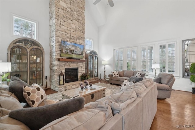 living room featuring a towering ceiling, a fireplace, and light hardwood / wood-style floors