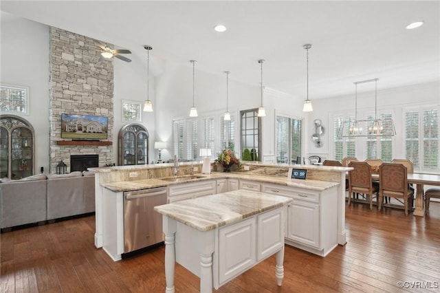 kitchen with white cabinetry, decorative light fixtures, dishwasher, and an island with sink