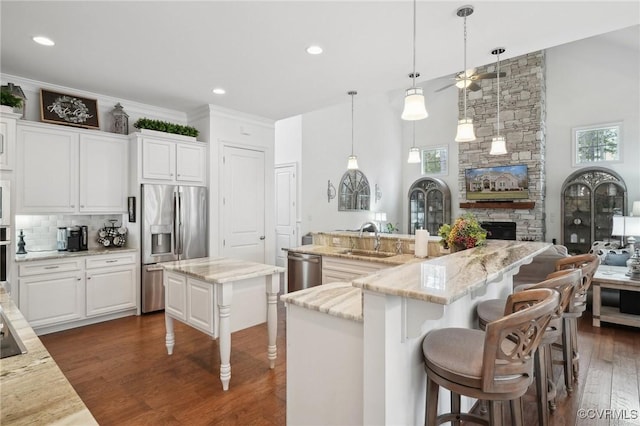 kitchen featuring decorative light fixtures, sink, a kitchen breakfast bar, stainless steel appliances, and a center island with sink