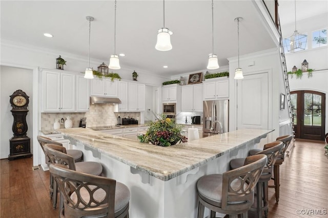 kitchen with backsplash, decorative light fixtures, white cabinets, and appliances with stainless steel finishes