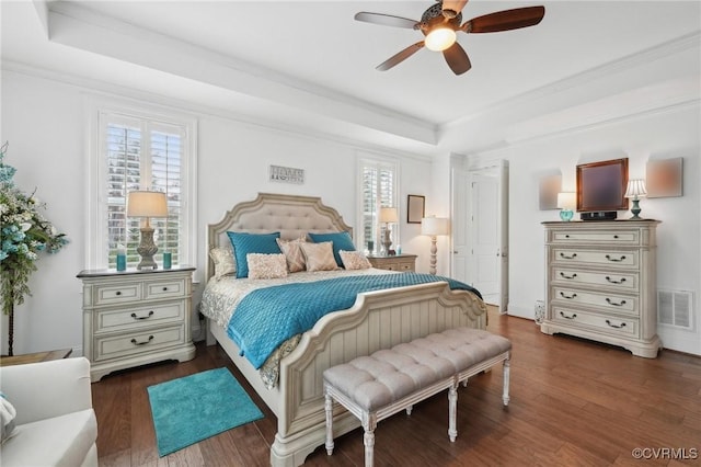 bedroom featuring crown molding, dark hardwood / wood-style floors, a raised ceiling, and ceiling fan