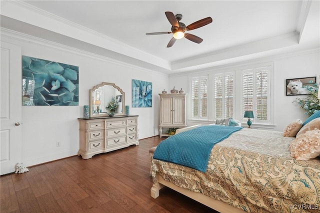 bedroom with dark wood-type flooring, ceiling fan, a tray ceiling, and crown molding