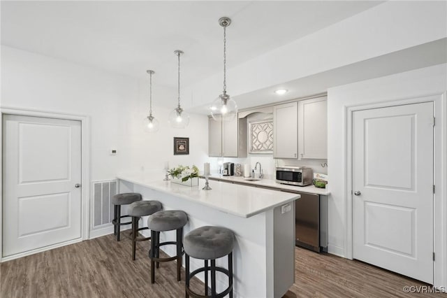 kitchen featuring sink, a kitchen breakfast bar, dark hardwood / wood-style floors, decorative light fixtures, and kitchen peninsula