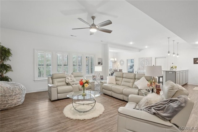 living room with hardwood / wood-style floors and ceiling fan with notable chandelier