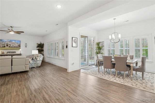 dining space with wood-type flooring, a healthy amount of sunlight, and ceiling fan with notable chandelier