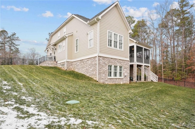 view of side of property with a sunroom and a lawn