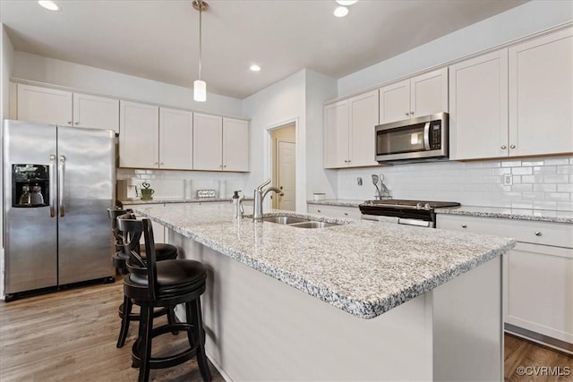 kitchen with sink, white cabinetry, stainless steel appliances, and hanging light fixtures