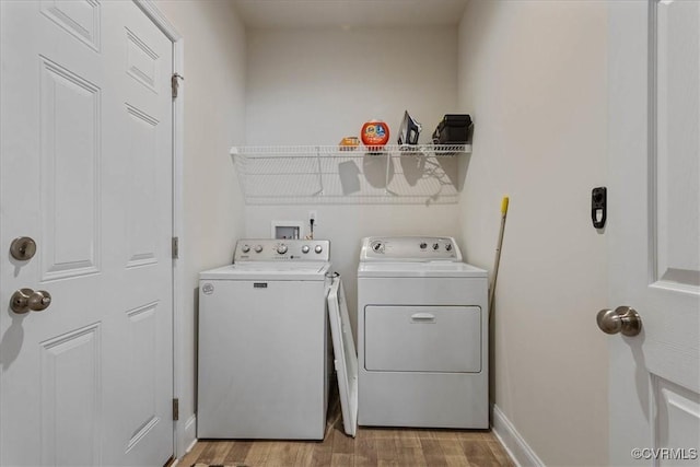 washroom with light hardwood / wood-style flooring and washing machine and clothes dryer