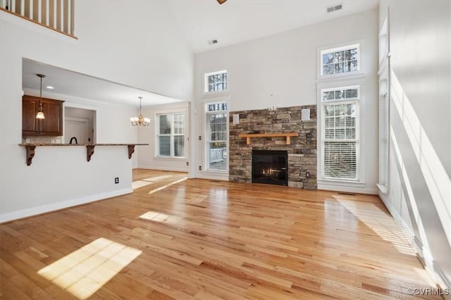 unfurnished living room featuring a stone fireplace, light hardwood / wood-style floors, and a towering ceiling