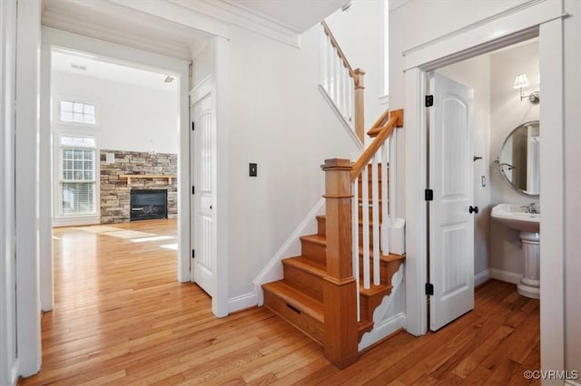 staircase featuring hardwood / wood-style flooring, ornamental molding, and a fireplace