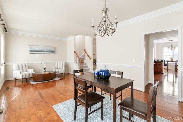 dining area with hardwood / wood-style floors, an inviting chandelier, and ornamental molding