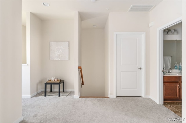 corridor featuring sink and light colored carpet