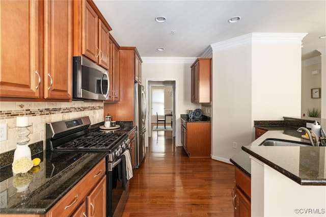 kitchen with appliances with stainless steel finishes, dark stone countertops, sink, backsplash, and dark hardwood / wood-style floors