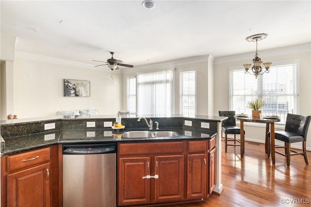 kitchen featuring sink, stainless steel dishwasher, decorative light fixtures, and dark stone counters