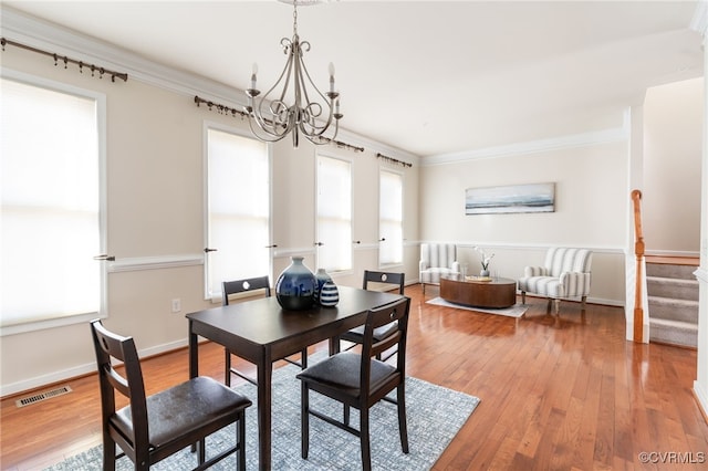 dining space with hardwood / wood-style floors, a chandelier, and ornamental molding