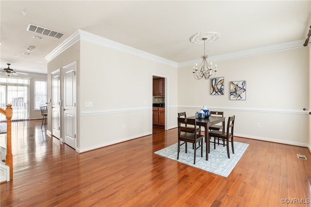 dining area featuring hardwood / wood-style flooring, crown molding, and ceiling fan with notable chandelier