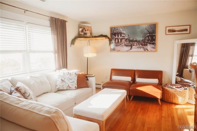 living room with hardwood / wood-style flooring, a baseboard radiator, and a healthy amount of sunlight