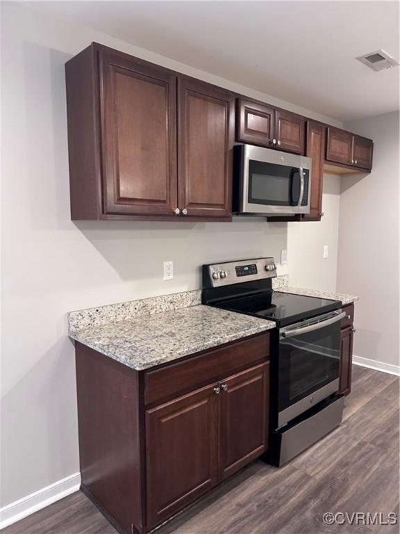 kitchen featuring stainless steel appliances, dark hardwood / wood-style floors, light stone countertops, and dark brown cabinets