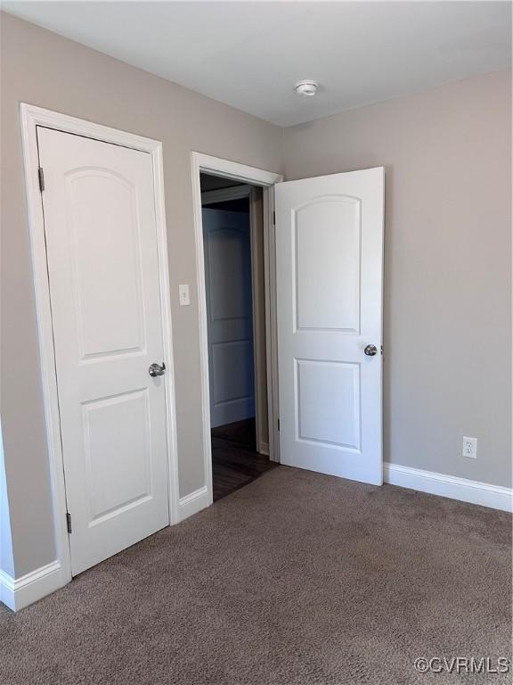 unfurnished bedroom with dark carpet