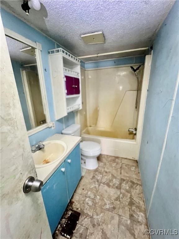 full bathroom featuring toilet, vanity, a textured ceiling, and washtub / shower combination