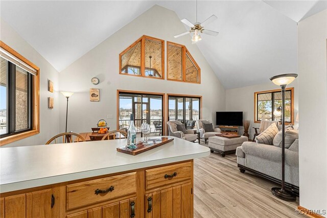 kitchen with light wood-type flooring, high vaulted ceiling, and ceiling fan