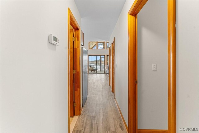 hallway with light hardwood / wood-style flooring and lofted ceiling