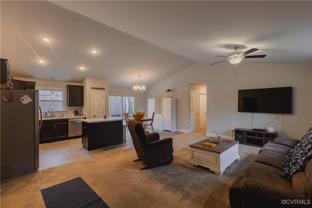 living room featuring ceiling fan with notable chandelier, lofted ceiling, light colored carpet, and sink