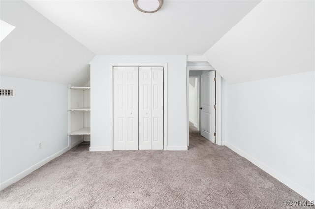 interior space featuring carpet flooring, vaulted ceiling, and a closet