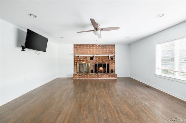 unfurnished living room featuring ceiling fan, dark hardwood / wood-style floors, and a fireplace