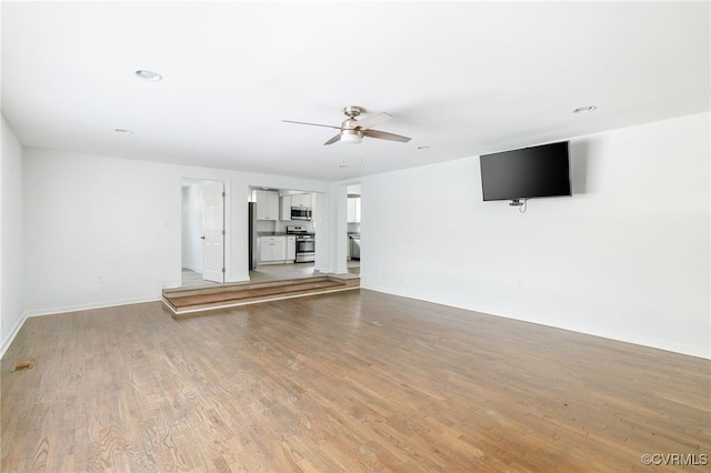 unfurnished living room with ceiling fan and light hardwood / wood-style flooring