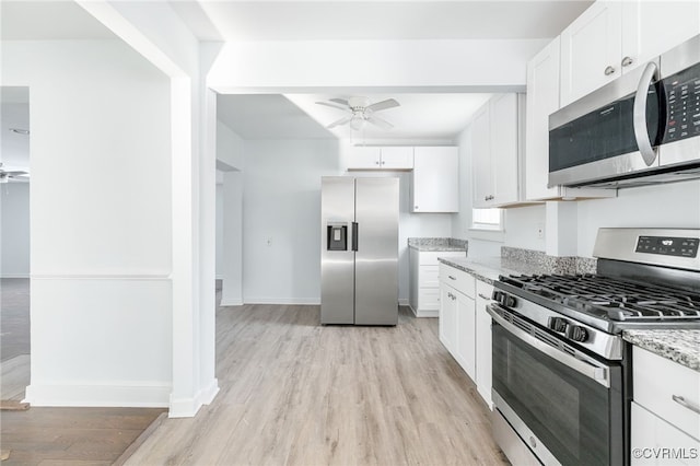 kitchen with ceiling fan, white cabinetry, stainless steel appliances, light stone countertops, and light wood-type flooring