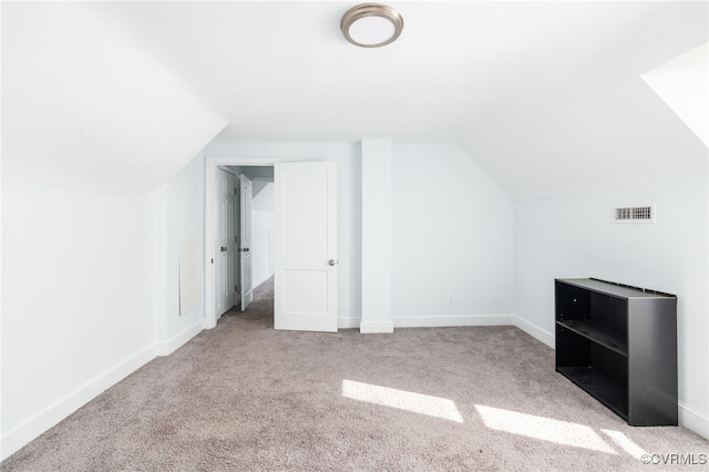 additional living space featuring vaulted ceiling and light carpet