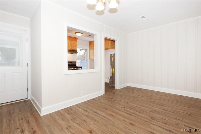 spare room featuring hardwood / wood-style floors, ornamental molding, and a notable chandelier