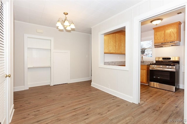 dining space with an inviting chandelier, ornamental molding, and hardwood / wood-style flooring