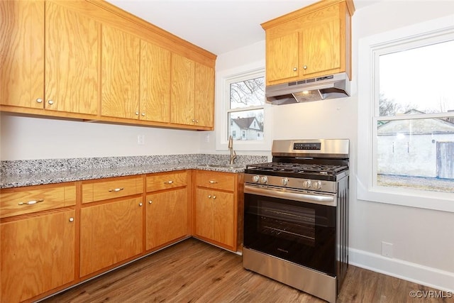 kitchen featuring dark wood-type flooring, stainless steel gas range, sink, and light stone countertops