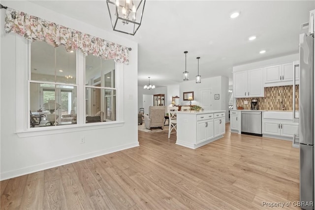 kitchen featuring white cabinetry, appliances with stainless steel finishes, decorative backsplash, pendant lighting, and a center island