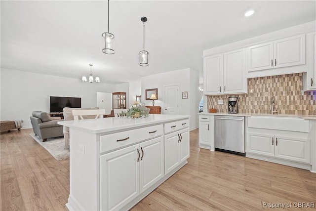 kitchen with decorative backsplash, pendant lighting, stainless steel dishwasher, and white cabinets