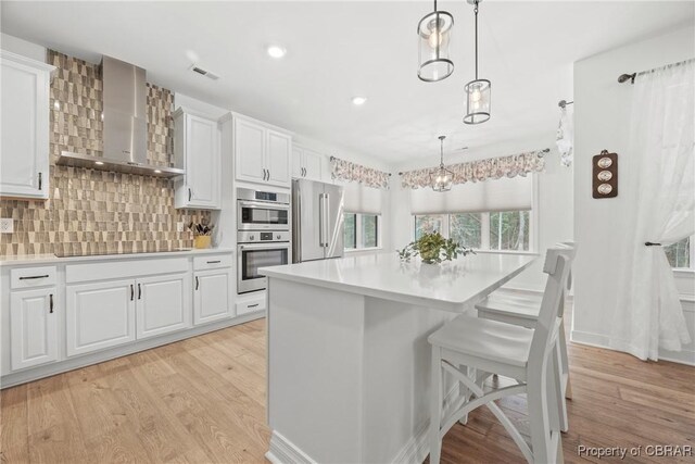 11293 Bayport Lndg, Gloucester, VA 23003 - kitchen featuring wall chimney exhaust hood, stainless steel appliances, light wood finished floors, light countertops, and white cabinets