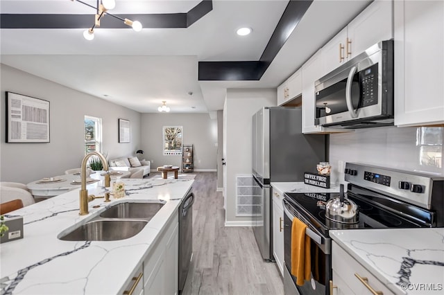 kitchen featuring sink, white cabinetry, light wood-type flooring, stainless steel appliances, and light stone counters