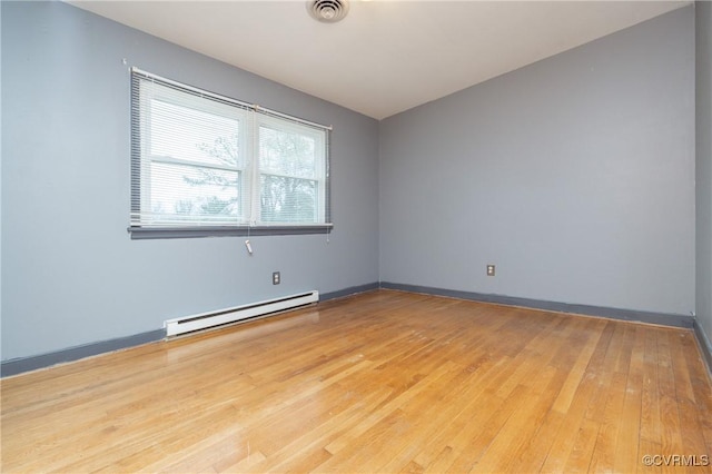 empty room featuring baseboard heating and light hardwood / wood-style flooring