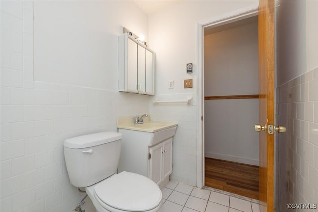 bathroom featuring tile patterned flooring, vanity, toilet, and tile walls