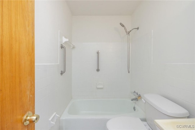 bathroom with tiled shower / bath, toilet, and tile walls