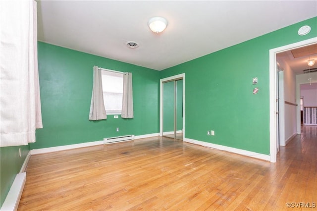 empty room with a baseboard radiator and light wood-type flooring