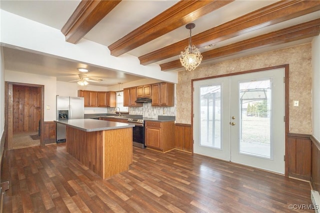 kitchen featuring decorative light fixtures, a center island, appliances with stainless steel finishes, dark hardwood / wood-style floors, and beam ceiling