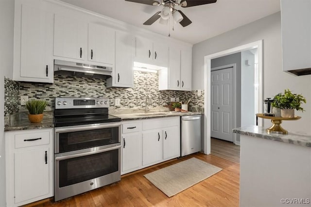 kitchen featuring white cabinets, stainless steel appliances, tasteful backsplash, sink, and light wood-type flooring