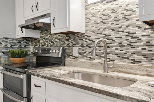 kitchen with white cabinets, double oven range, decorative backsplash, and sink