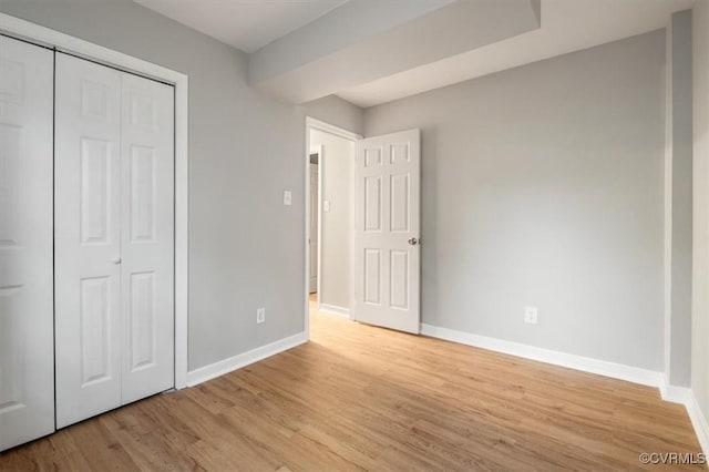 unfurnished bedroom with light wood-type flooring and a closet