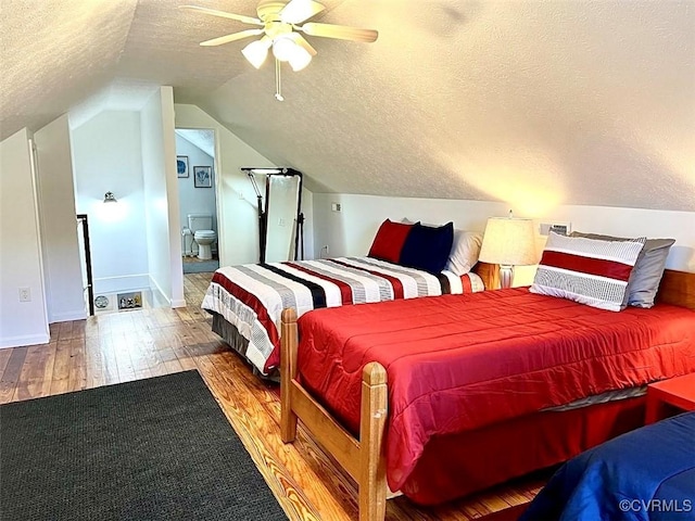 bedroom with ensuite bath, vaulted ceiling, a textured ceiling, hardwood / wood-style flooring, and ceiling fan