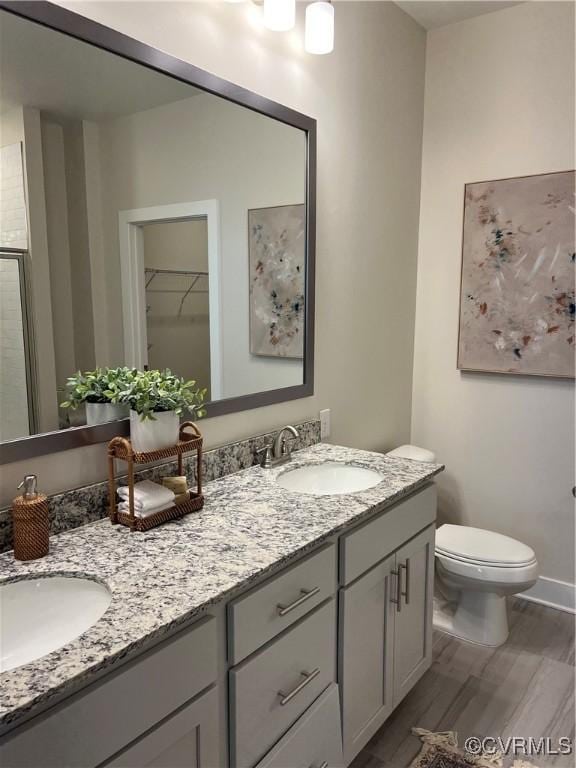 bathroom with toilet, vanity, an enclosed shower, and hardwood / wood-style flooring